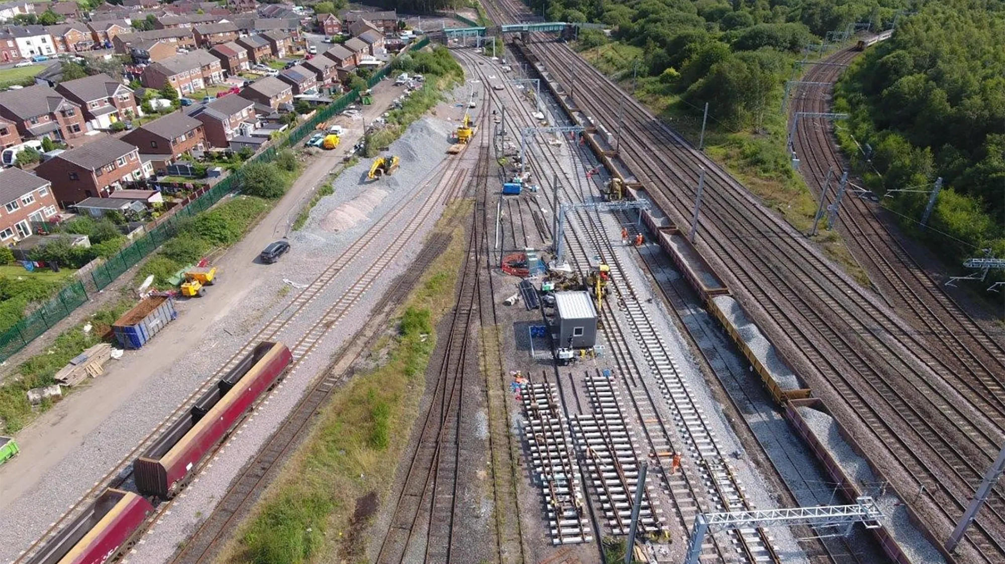 Aerial view of a railway depot with multiple train tracks, construction work and nearby residential houses