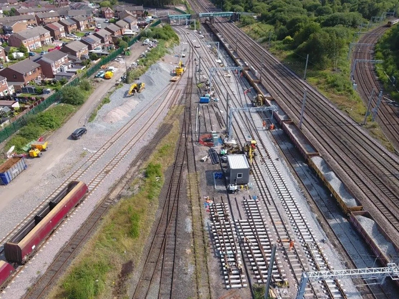 Aerial view of a railway depot with multiple train tracks, construction work and nearby residential houses