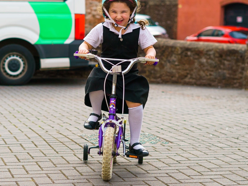 A smiling female child riding on a bicycle