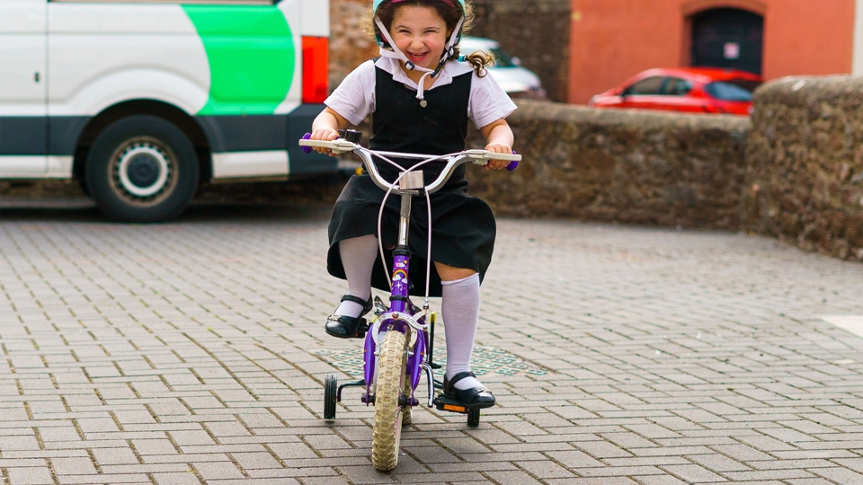 A smiling female child riding on a bicycle