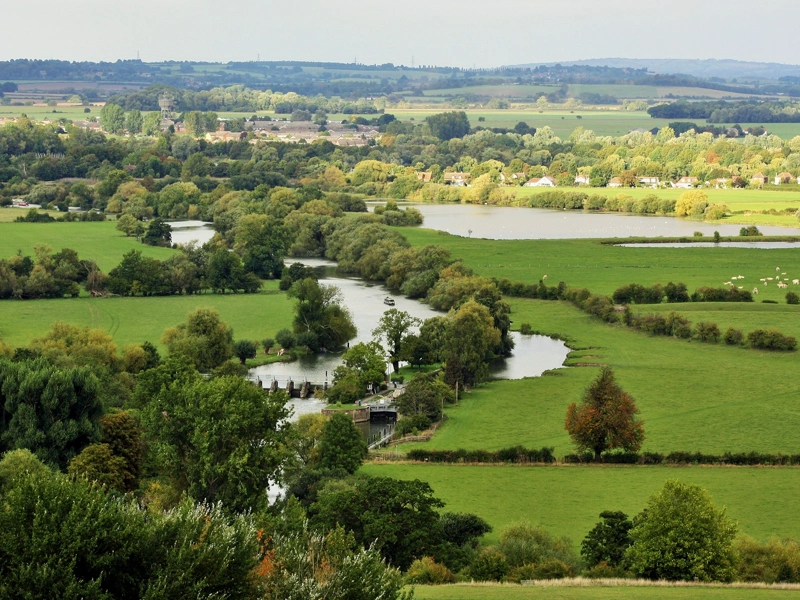Aerial view of water in amongst a green landscape of fields and farmland