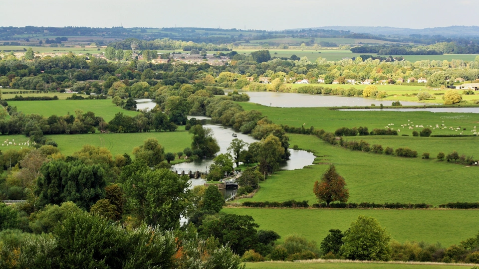 Aerial view of water in amongst a green landscape of fields and farmland