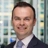 Portrait of Chris Swann, Associate Director, Advisory and Consulting, with city landscape featuring building with lots of windows in the background.