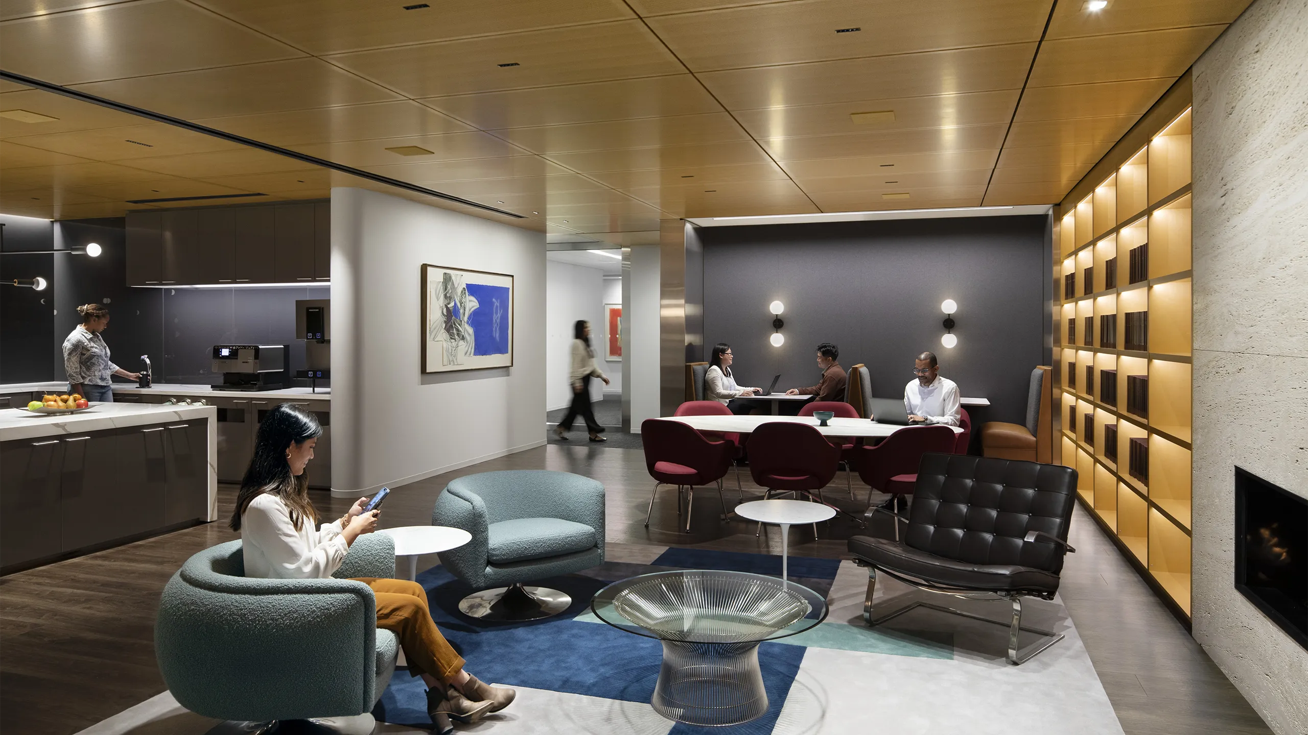 A breakout room and kitchen in a modern office with employees in conversation