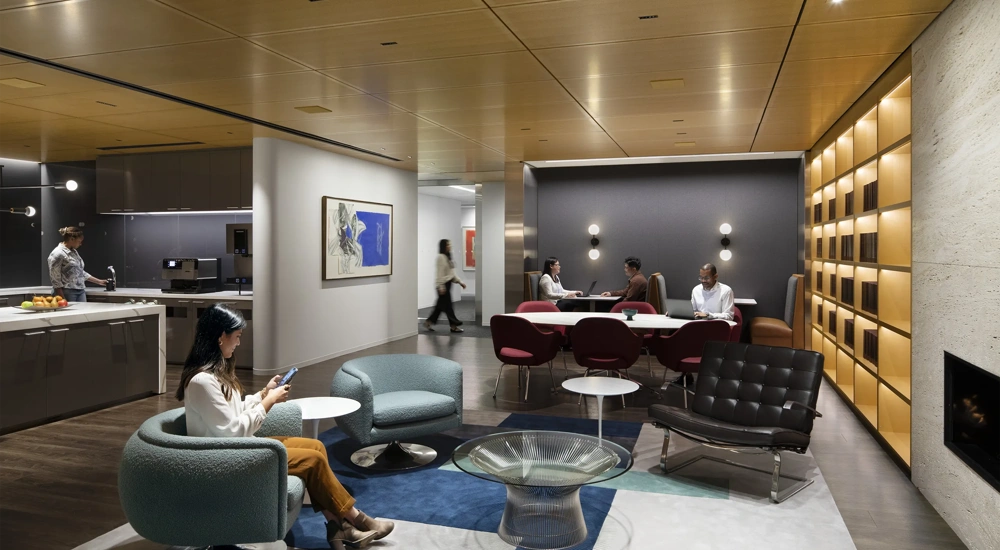 A breakout room and kitchen in a modern office with employees in conversation