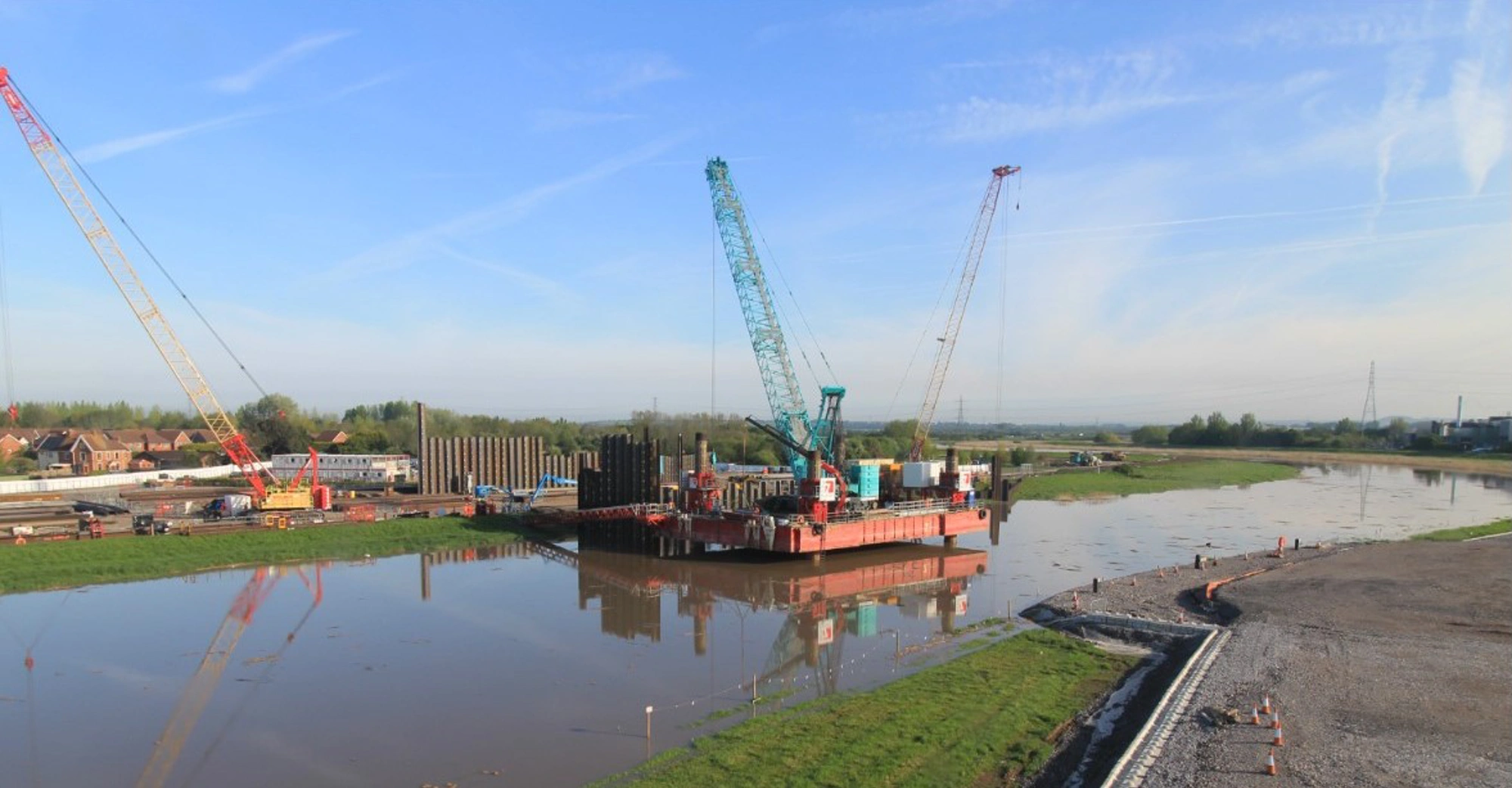 Barge with cranes working on a river flood barrier construction site in the UK