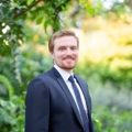 Portrait of Joe Connolly, Industrial and Logistics Lead, North America, Standing outside infront of green plants smiling.