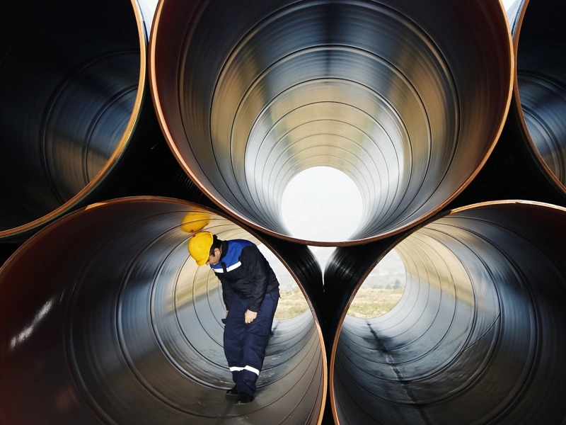 Man with yellow hard hat standing inside large cylinder