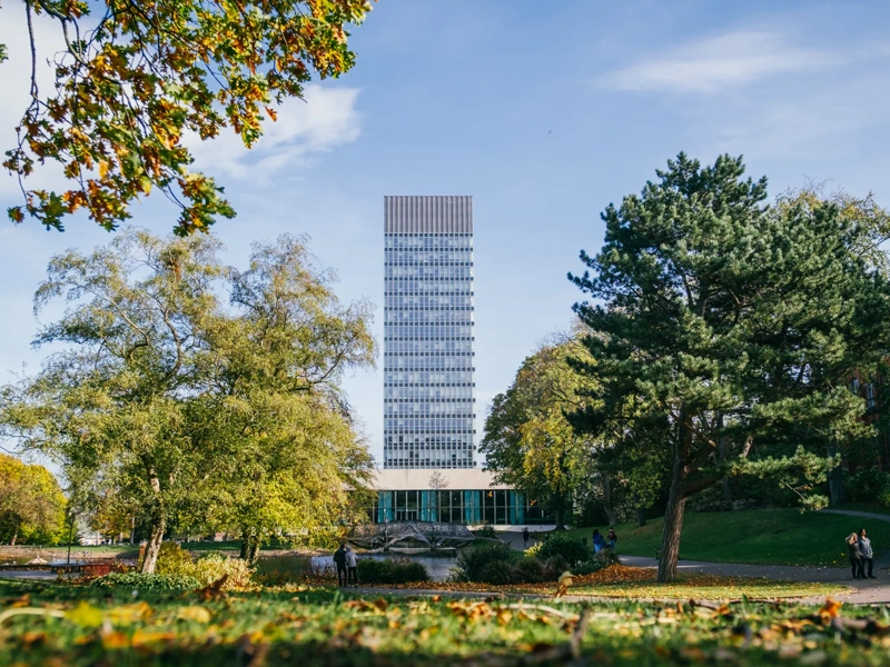 University campus with trees and a tall modern building in background