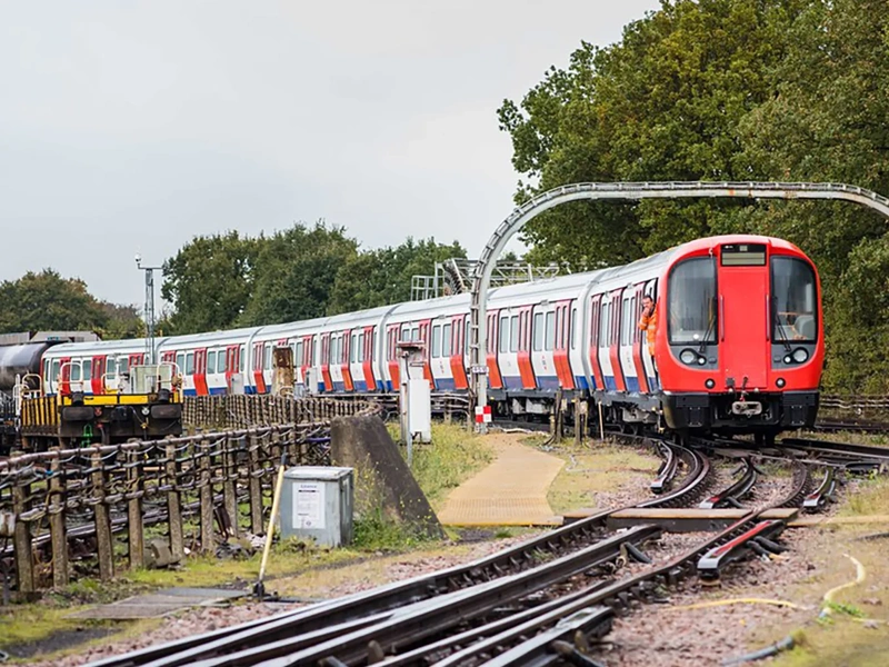 Driverless train approaching station in london's docklands area on a sunny day.