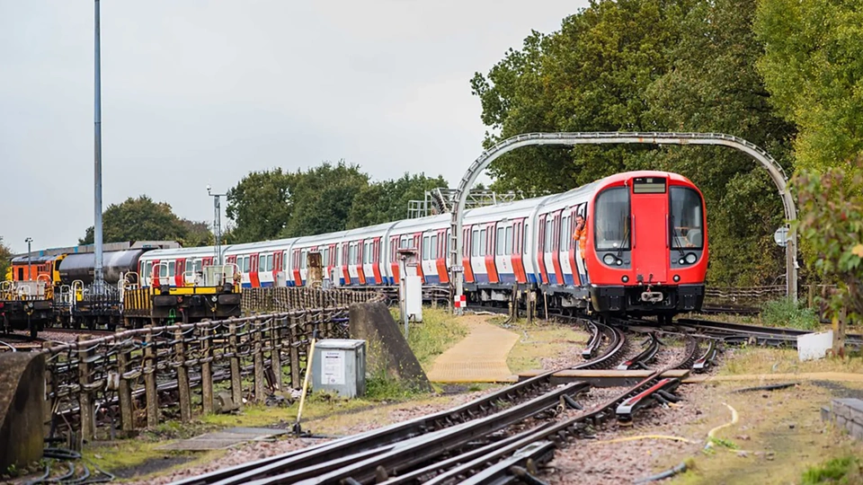 Driverless train approaching station in london's docklands area on a sunny day.