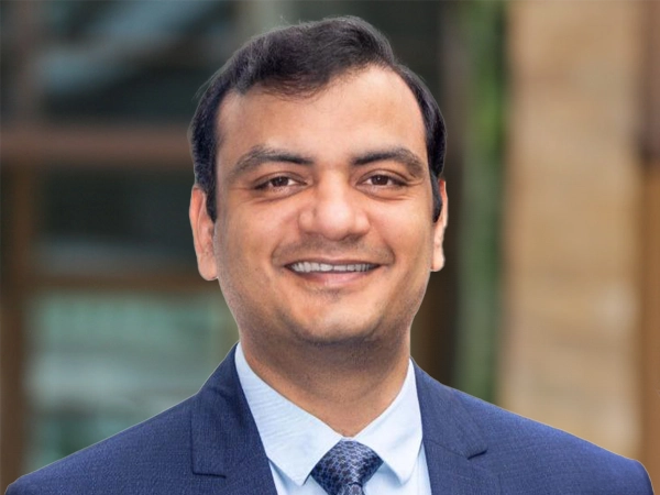 Portrait of Ashish Jain, Country Manager, outside in front of a blurred brown background featuring a building and mix of natural and urban elements.