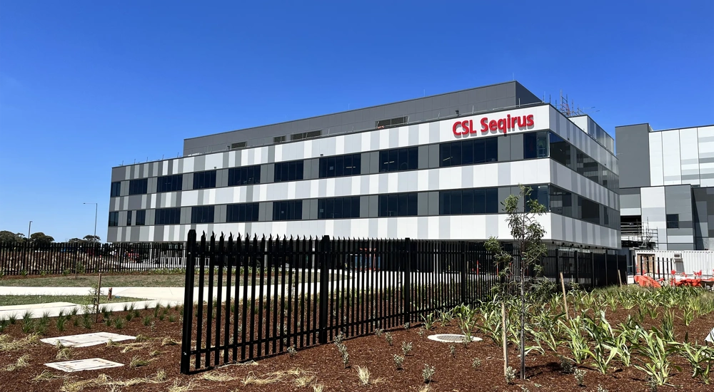 A CSL Seqirus vaccine facility, a multi-storey building set against a blue sky.