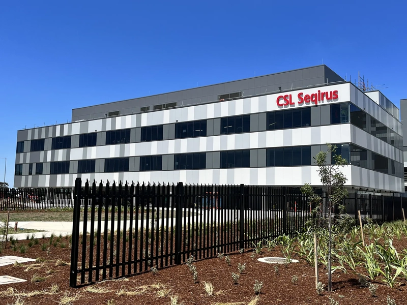 A CSL Seqirus vaccine facility, a multi-storey building set against a blue sky.
