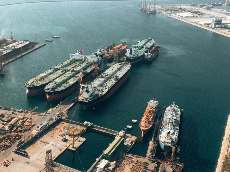 Image of maritime boats pulling up to harbor, with blue sea.