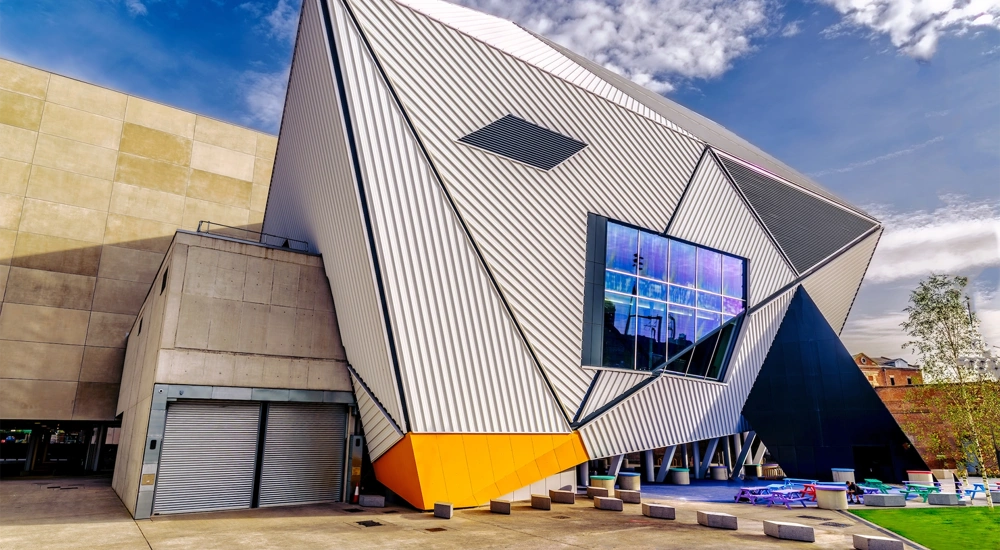 Modern, corrugated building of dynamic angles against a blue sky