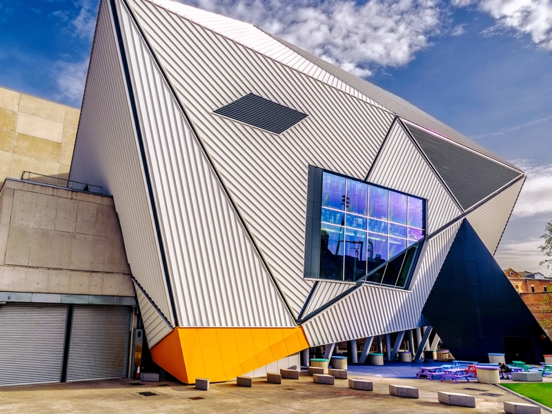 Modern, corrugated building of dynamic angles against a blue sky
