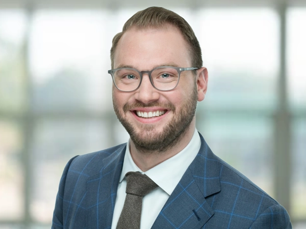 Portrait of Maximilian Frisch, Associate Director, in front of a glass office building