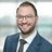 Portrait of Maximilian Frisch, Associate Director, in front of a glass office building