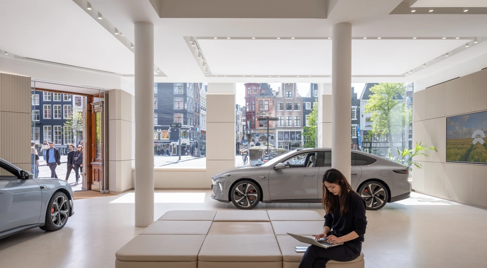 Interior of NIO House Amsterdam ground floor showroom with two cars against backdrop of amsterdam through the windows, The Netherlands