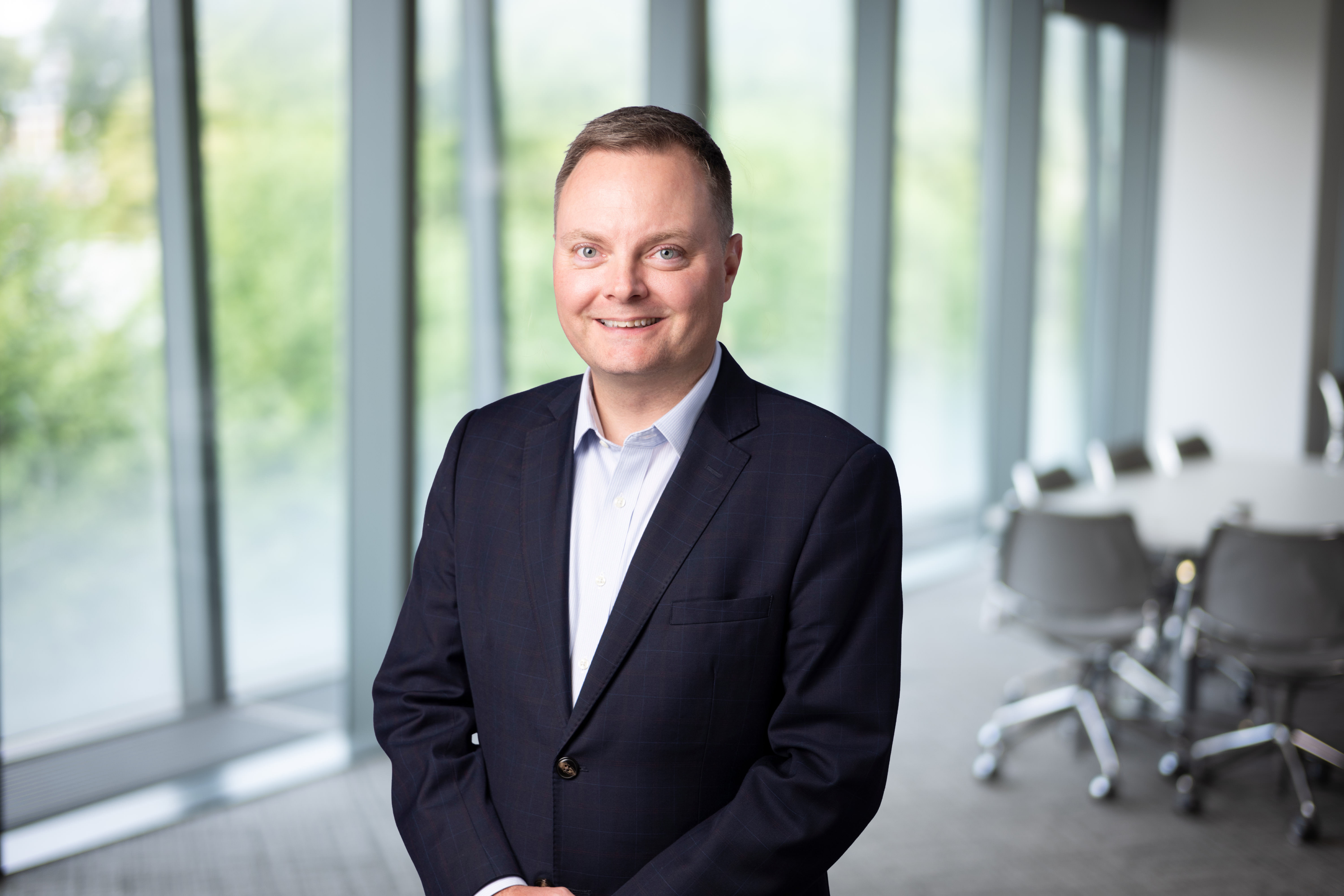 Portrait of Brian Shuptrine, Regional Managing Director, Asia, with city landscape featuring building with lots of windows in the background.