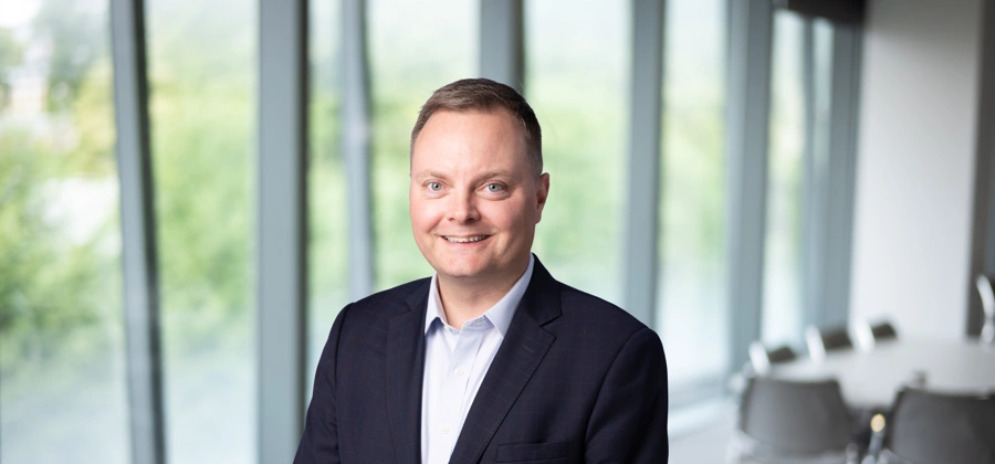 Portrait of Brian Shuptrine, Regional Managing Director, Asia, with city landscape featuring building with lots of windows in the background.