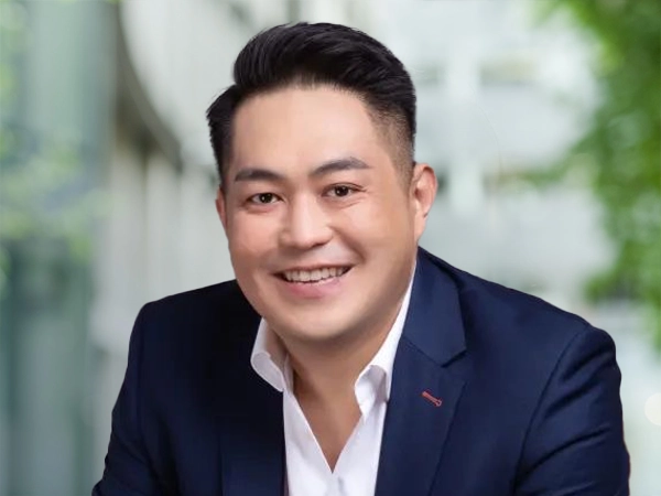 Portrait of Terence Koh, Project Director, standing outside in front of an outdoor urban setting, featuring modern architectural elements with clean lines. 