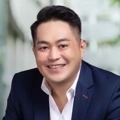 Portrait of Terence Koh, Project Director, standing outside in front of an outdoor urban setting, featuring modern architectural elements with clean lines.