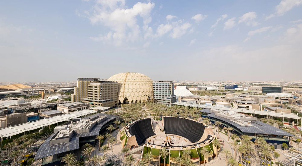 Ariel view of Dubai Expo, modern city complex with large building, curved structures and surrounding roads under a clear sky