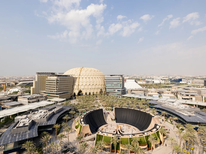 Ariel view of Dubai Expo, modern city complex with large building, curved structures and surrounding roads under a clear sky