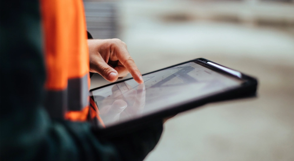 Person in orange hi vis vest using a digital tablet