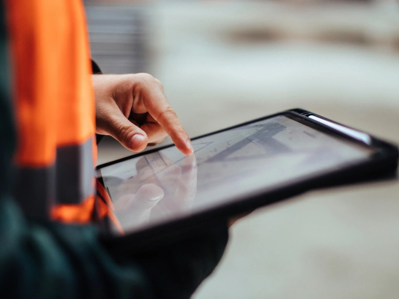 Person in orange hi vis vest using a digital tablet