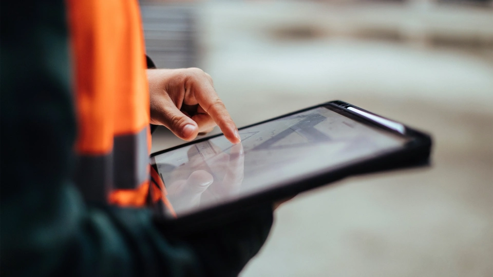 Person in orange hi vis vest using a digital tablet