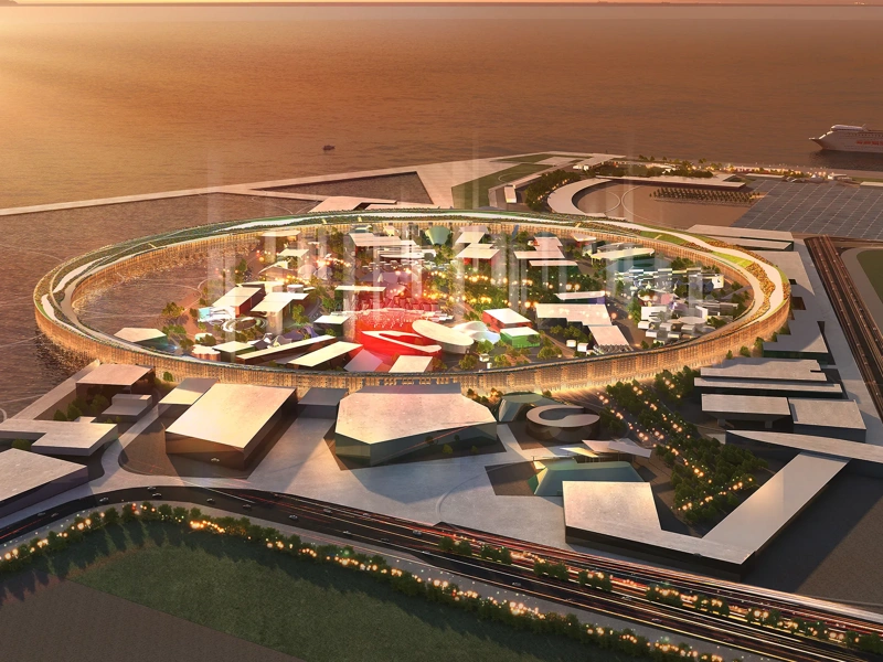 Ariel rendering of the Osaka Expo pavilion, Japan at sunset, showing a circular central structure surrounded by modern buildings and pathways within a large exhibition site.
