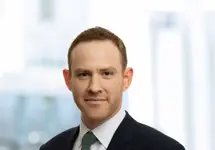 Portrait of Dave Carr, Associate Director, Corporate Occupier, UK, In black suit with green tie against window office.