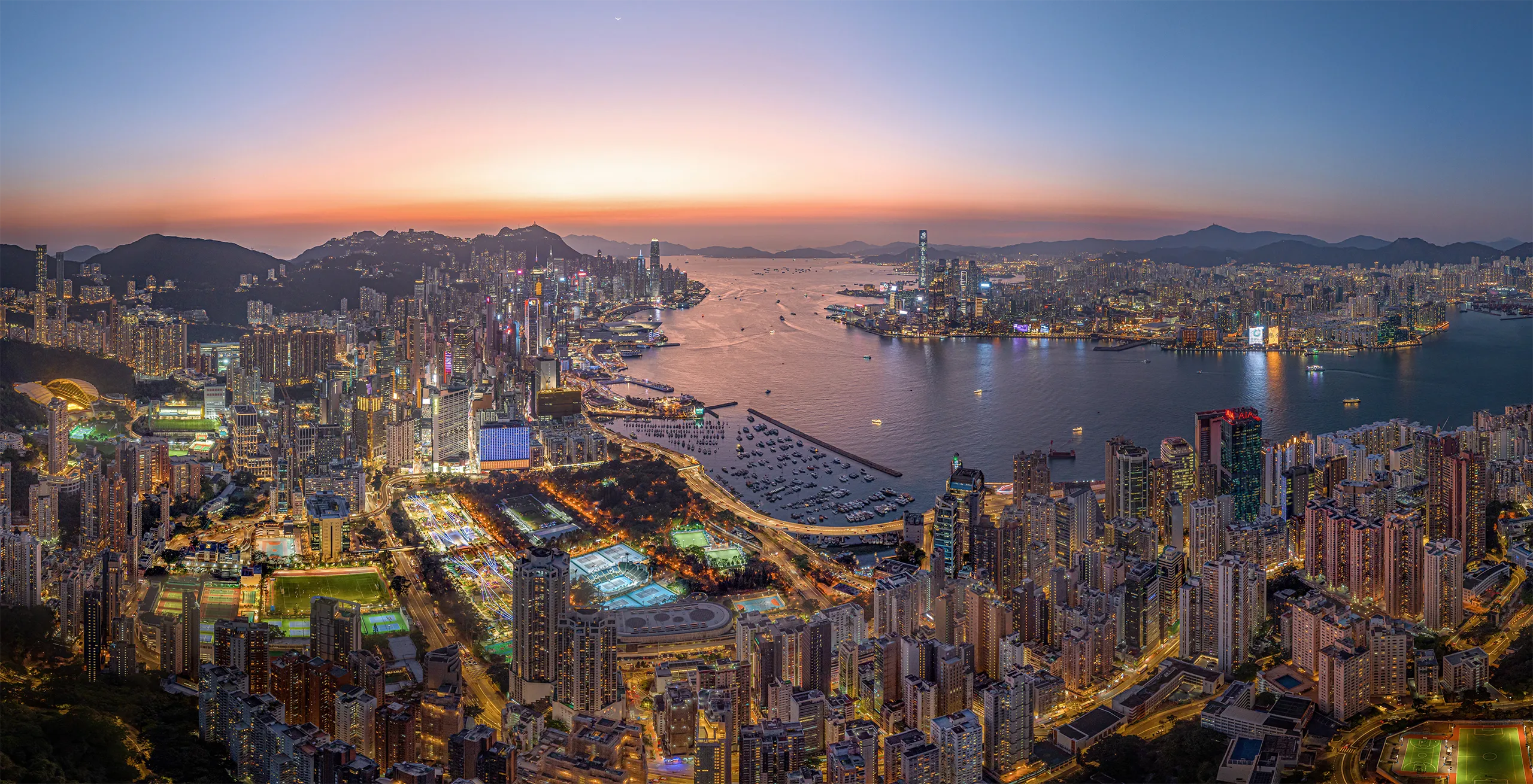 Aerial Drone of Hong Kong island cityscape skyline at night. Skyscraper building in financial, business district and urban lights reflecting on Victoria harbour