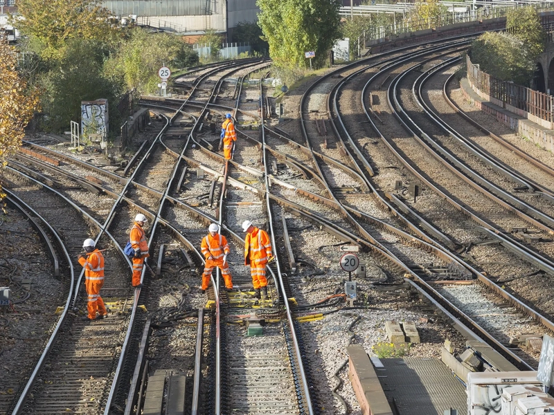 Construction workers in hard hats and high-vis gear on train tracks
