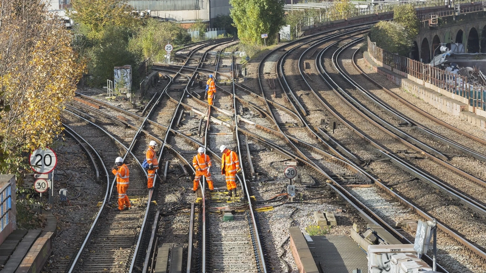 Construction workers in hard hats and high-vis gear on train tracks