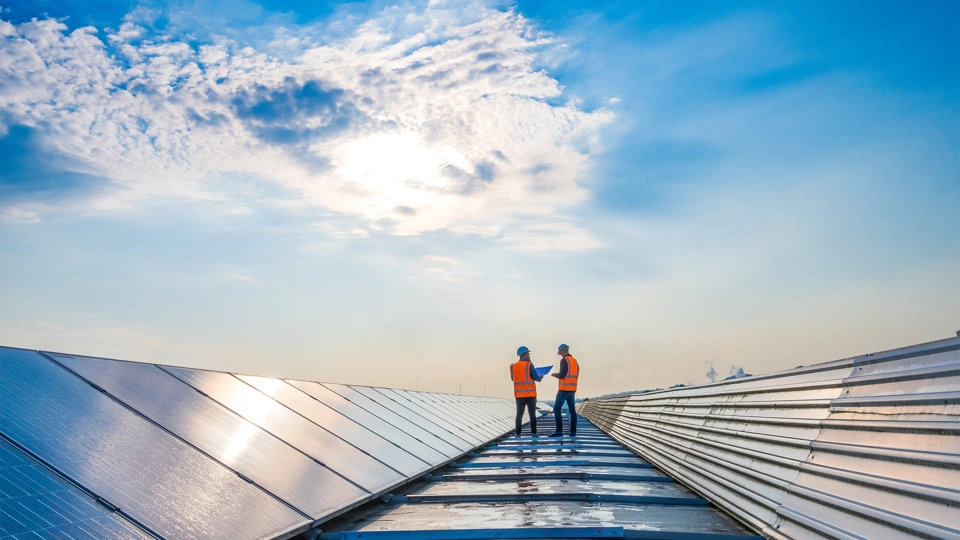 Two men in hi vis jackets standing on top of a solar panel farm