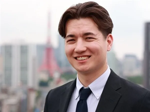 Portrait of Jin Parisien, Data Centre Services Lead, Asia, standing outside with city landscape in the background, smiling.