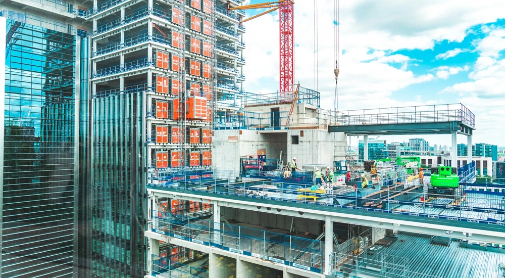 View at construction site with unfinished residential buildings against blue sky, London