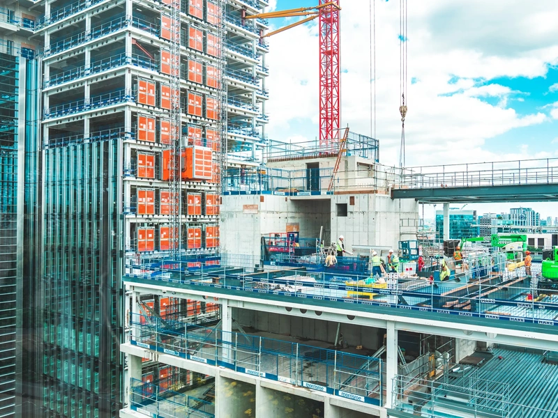 View at construction site with unfinished residential buildings against blue sky, London