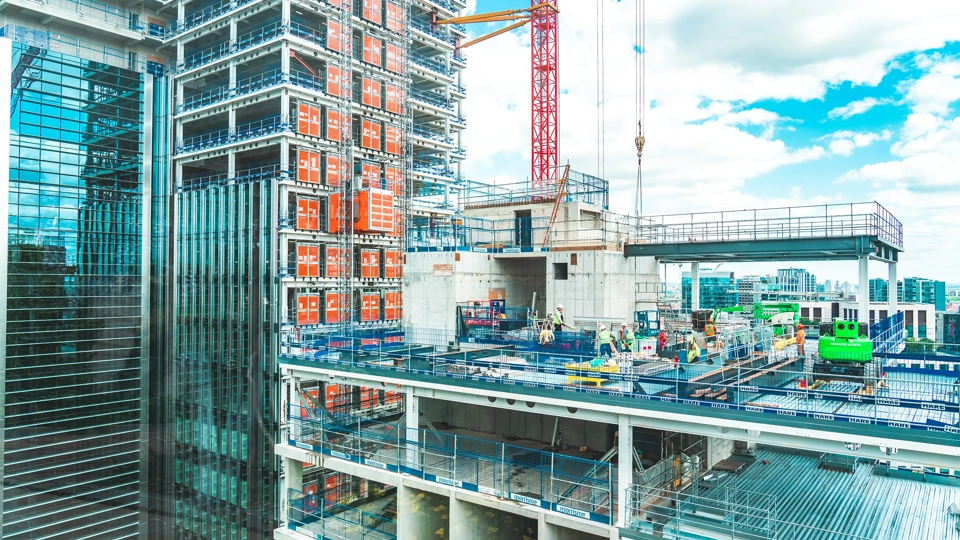 View at construction site with unfinished residential buildings against blue sky, London