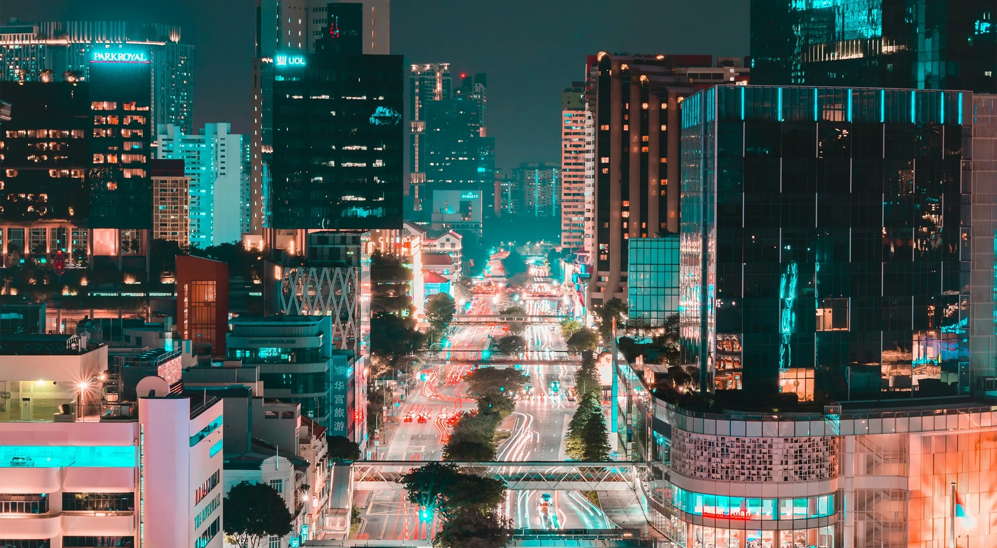 Singapore at night with glass skyscraper buildings and brightly lit roads with traffic