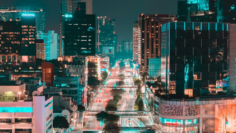 Singapore at night with glass skyscraper buildings and brightly lit roads with traffic