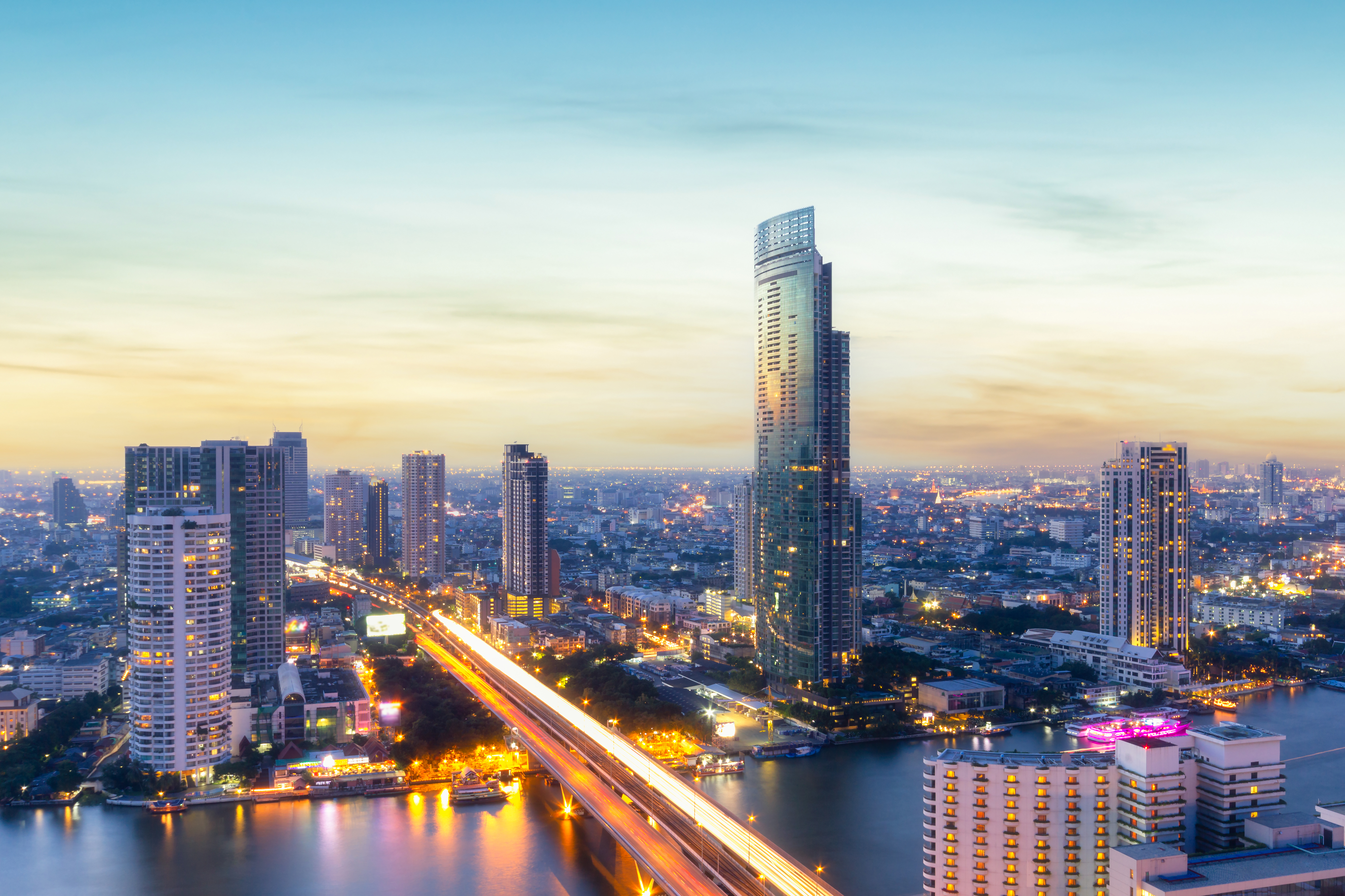Sunset view of Bangkok business district with tall skyscrapers in front of water
