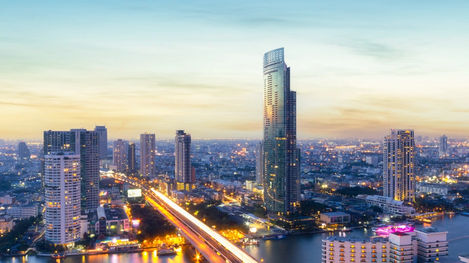 Sunset view of Bangkok business district with tall skyscrapers in front of water