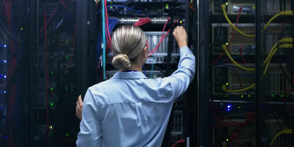 Woman in a data centre, reaching out for a cord