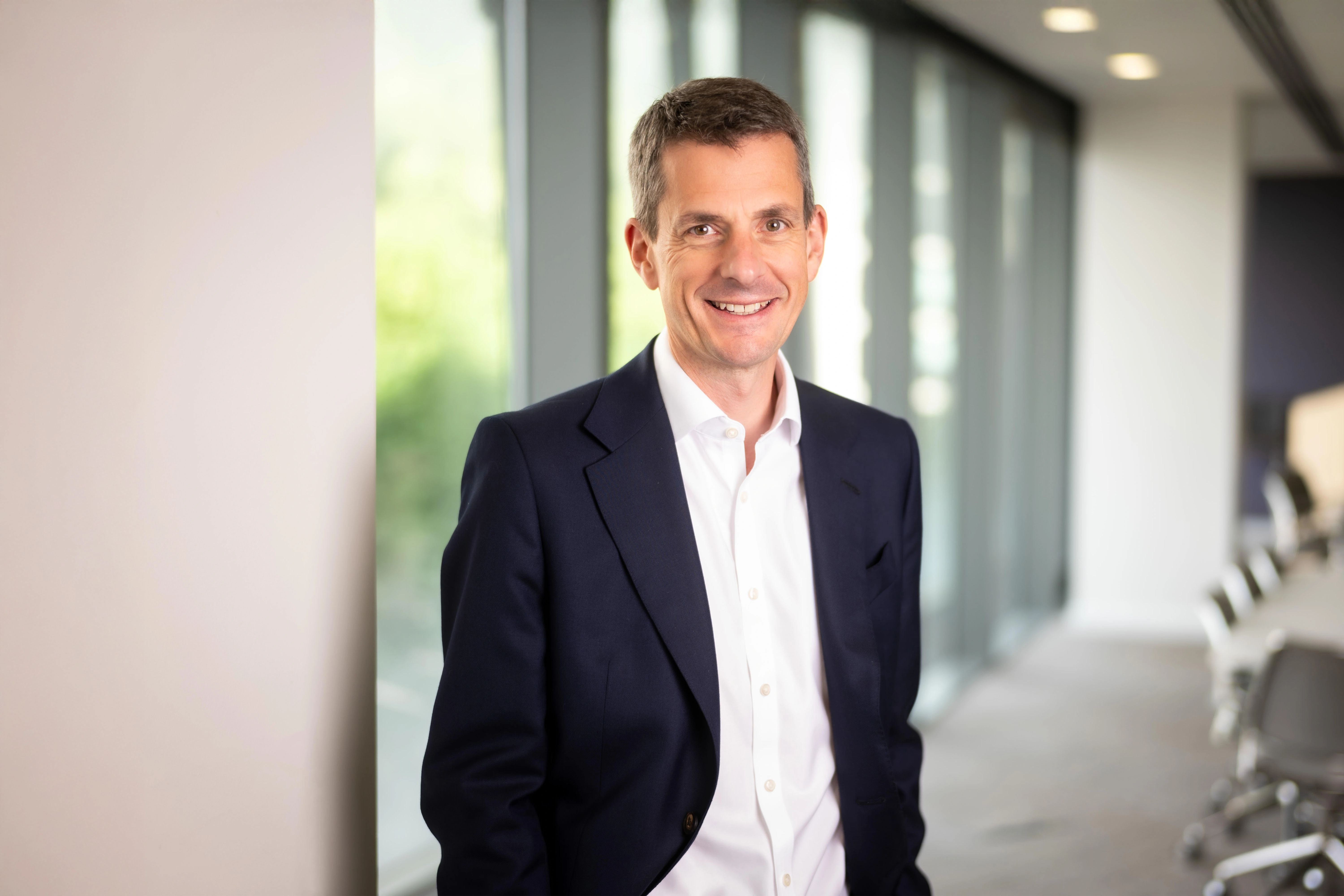 Finance Director, Richard Peers, smiling in an office interior in front of a window with trees