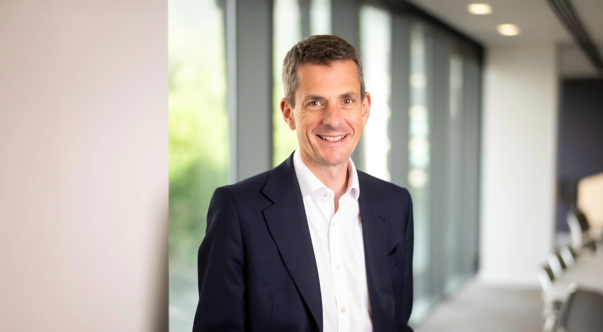 Finance Director, Richard Peers, smiling in an office interior in front of a window with trees